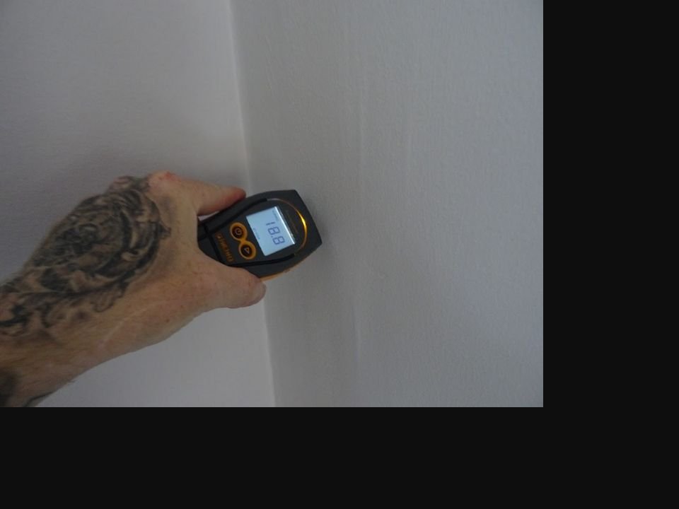 Surveyor taking a moisture meter reading from an internal wall during a Level 3 Building Survey